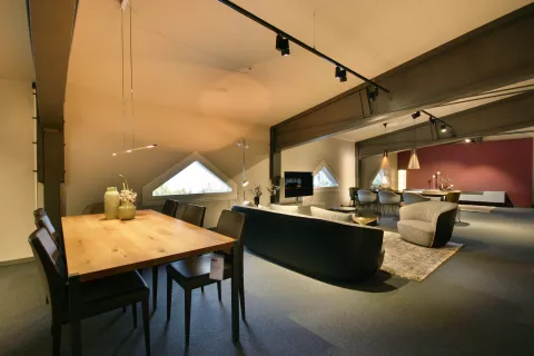 Ess- und Wohnbereich mit Holzesstisch und vier Stühle, graues Sofa, verschiedene Decken- und Pendelleuchten